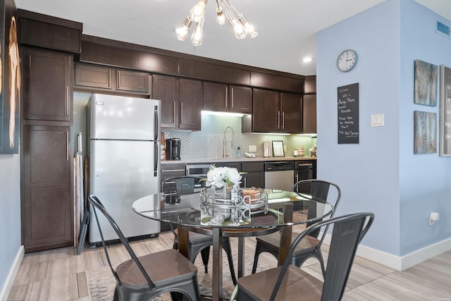 kitchen with dark brown cabinetry, light countertops, stainless steel dishwasher, freestanding refrigerator, and decorative backsplash