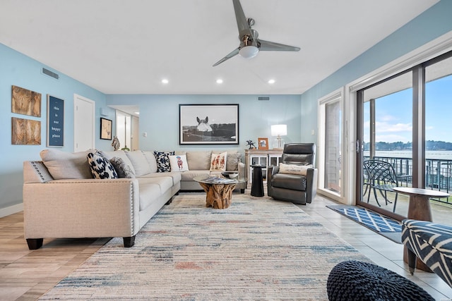 living room with baseboards, a water view, visible vents, and recessed lighting