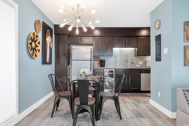 kitchen featuring dark brown cabinetry, light countertops, stainless steel dishwasher, backsplash, and freestanding refrigerator