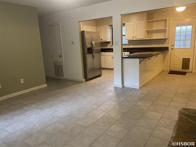 kitchen featuring visible vents, white cabinets, dark countertops, a peninsula, and stainless steel refrigerator with ice dispenser