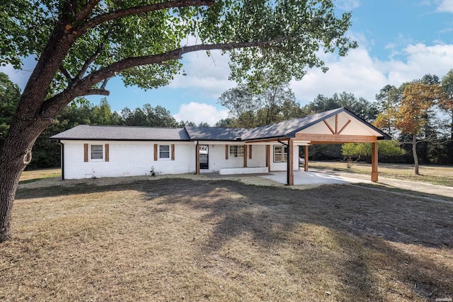 ranch-style house featuring brick siding, a carport, and a front yard