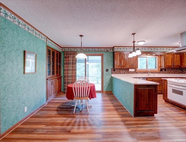 7 Sonora Way, Hot Springs Village, AR 71909 - kitchen featuring wallpapered walls, a textured ceiling, light wood-style flooring, white range with electric cooktop, and brown cabinets