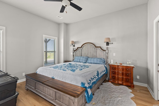 bedroom featuring ceiling fan, visible vents, baseboards, and wood finished floors