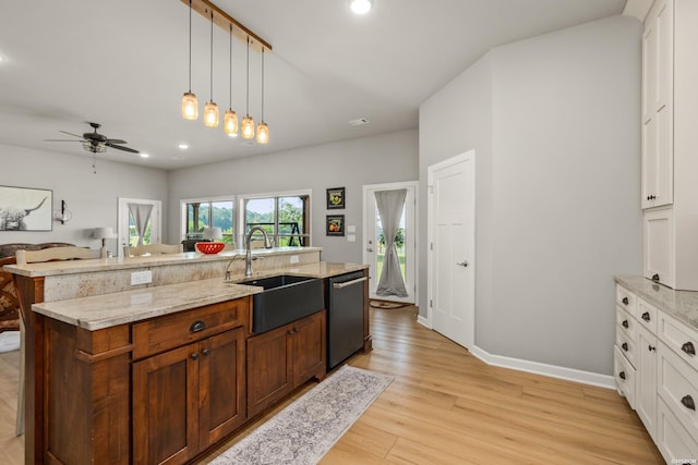 kitchen featuring a center island with sink, a sink, stainless steel dishwasher, light wood-style floors, and white cabinets