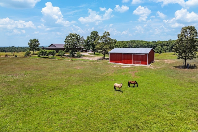 view of yard with a rural view, a detached garage, an outdoor structure, and a pole building