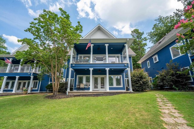 rear view of property with a balcony, a lawn, and french doors