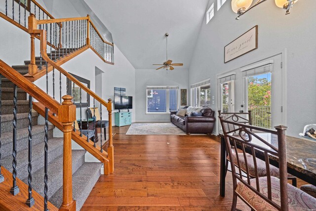 entrance foyer with a ceiling fan, stairs, high vaulted ceiling, and wood finished floors