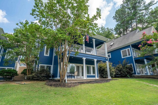 rear view of house featuring a lawn and a balcony