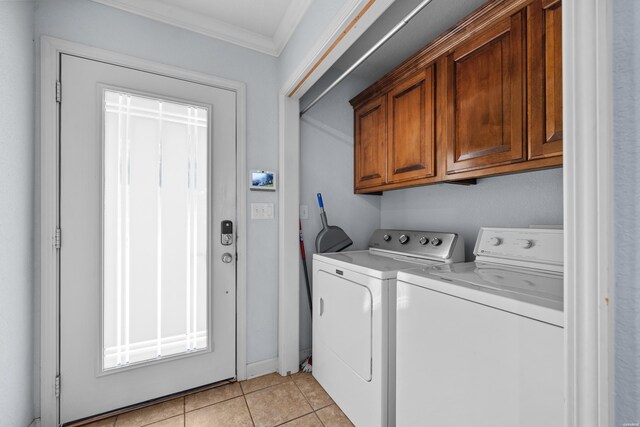 clothes washing area with light tile patterned floors, ornamental molding, independent washer and dryer, and cabinet space