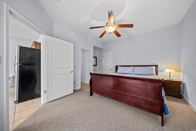 bedroom featuring light tile patterned floors, freestanding refrigerator, light carpet, ceiling fan, and baseboards