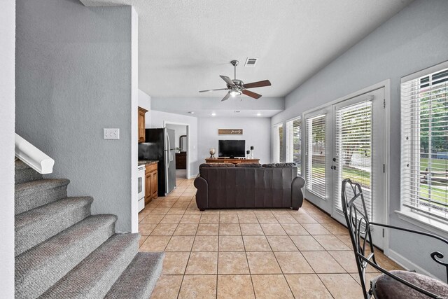 living area featuring stairs, a wealth of natural light, visible vents, and light tile patterned floors