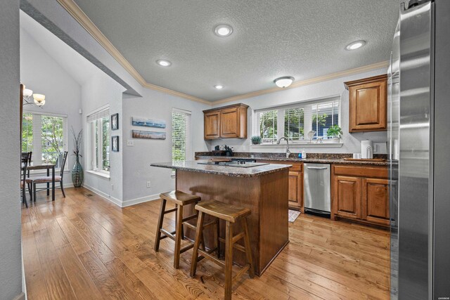 kitchen with brown cabinetry, freestanding refrigerator, a center island, and a breakfast bar