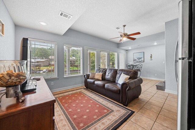 living room featuring visible vents, plenty of natural light, a textured ceiling, and light tile patterned floors