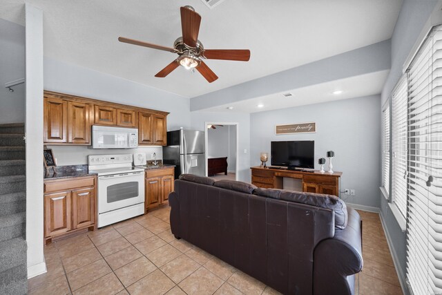 kitchen with white appliances, light tile patterned floors, a ceiling fan, dark countertops, and open floor plan