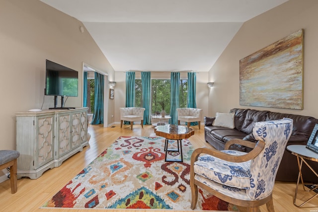 living area with vaulted ceiling, light wood-style flooring, and baseboards