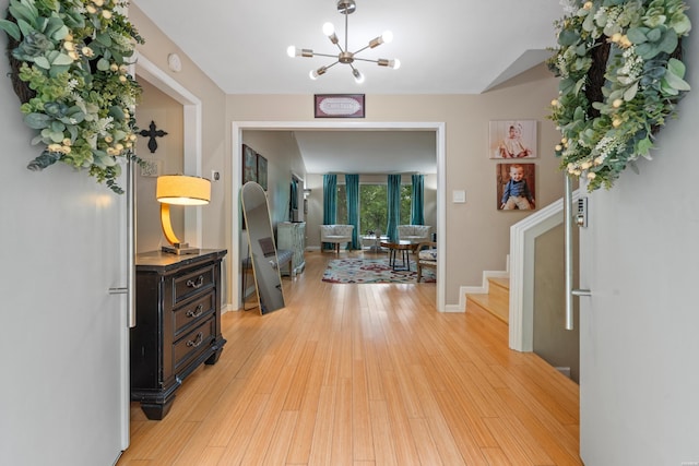 entryway with a chandelier, light wood-style flooring, stairs, and baseboards