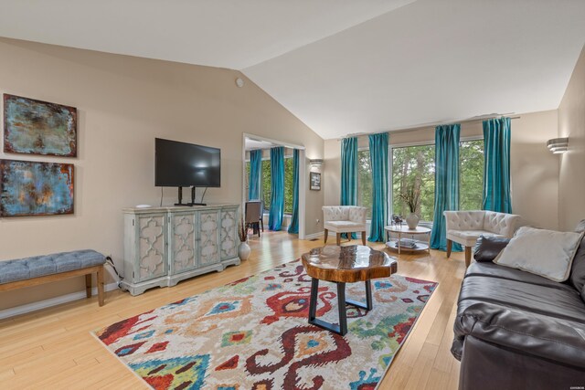 living room featuring vaulted ceiling, baseboards, and wood finished floors