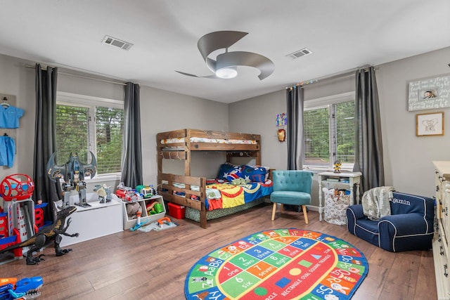 bedroom with multiple windows, wood-type flooring, and a ceiling fan