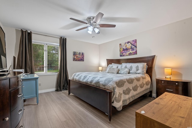 bedroom featuring baseboards, light wood finished floors, and ceiling fan