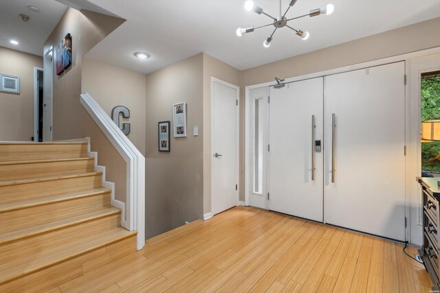 foyer entrance featuring a chandelier, light wood-style floors, stairs, and recessed lighting