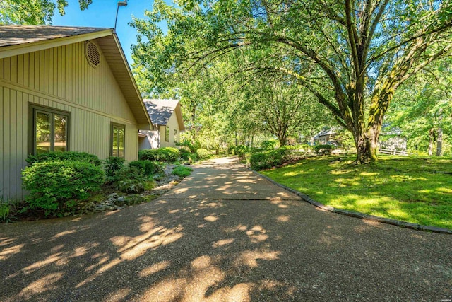 view of side of home with a shingled roof and a yard