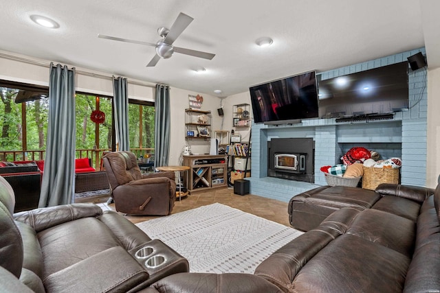 tiled living area with a fireplace and ceiling fan