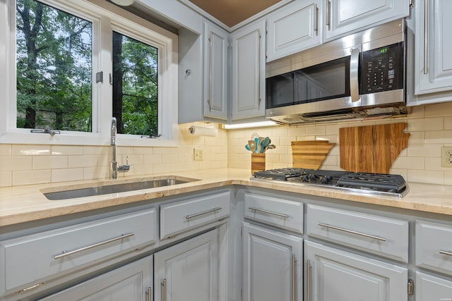 kitchen with stainless steel appliances, a sink, decorative backsplash, and white cabinetry