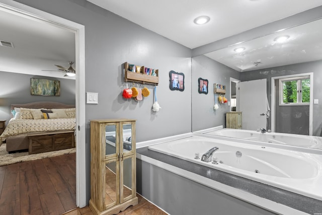 ensuite bathroom featuring a jetted tub and a ceiling fan