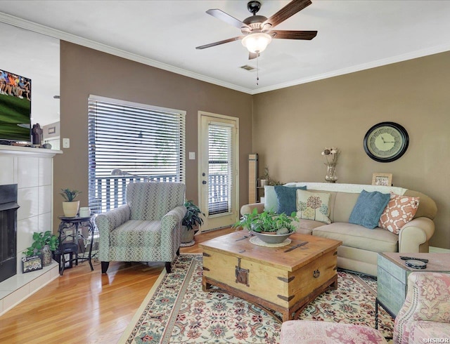 400 Farr Shores Dr Unit 15F, Hot Springs, AR 71913 - living room with light wood finished floors, a tiled fireplace, ceiling fan, visible vents, and crown molding