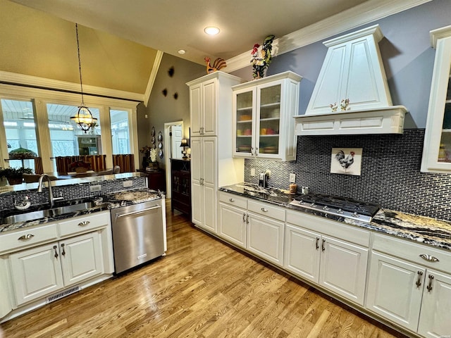 kitchen featuring appliances with stainless steel finishes, premium range hood, a sink, and glass insert cabinets