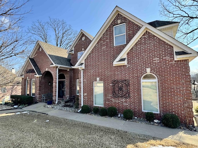 traditional home featuring brick siding and a shingled roof