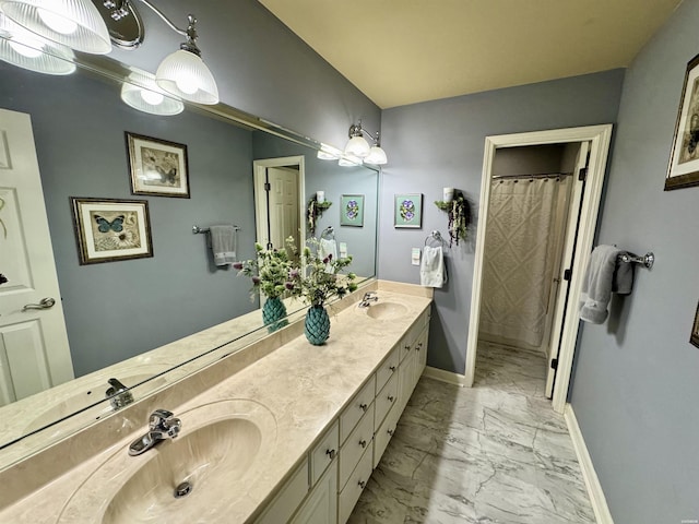 full bath featuring marble finish floor, a sink, baseboards, and double vanity