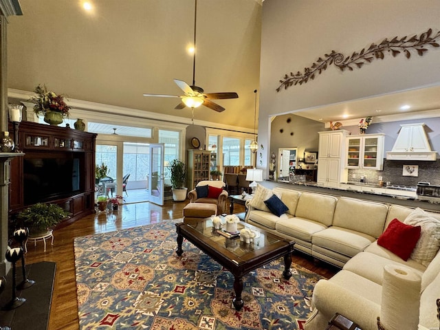 living area featuring ceiling fan, a high ceiling, dark wood finished floors, and crown molding