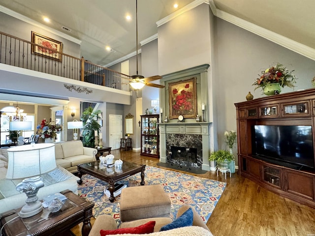 living room featuring baseboards, a premium fireplace, wood finished floors, a high ceiling, and crown molding