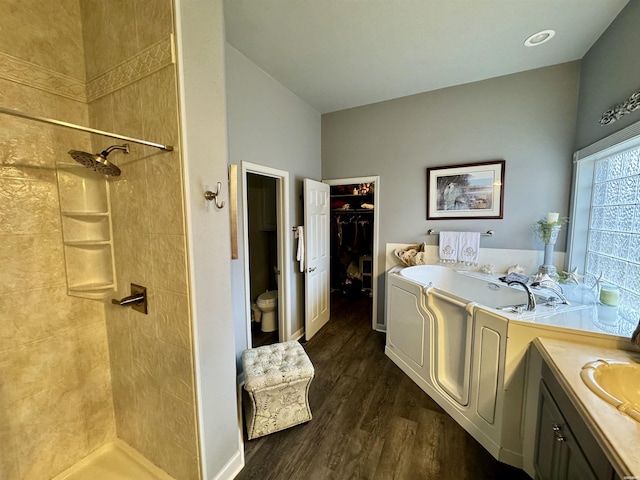 bathroom featuring toilet, a garden tub, a shower stall, and wood finished floors