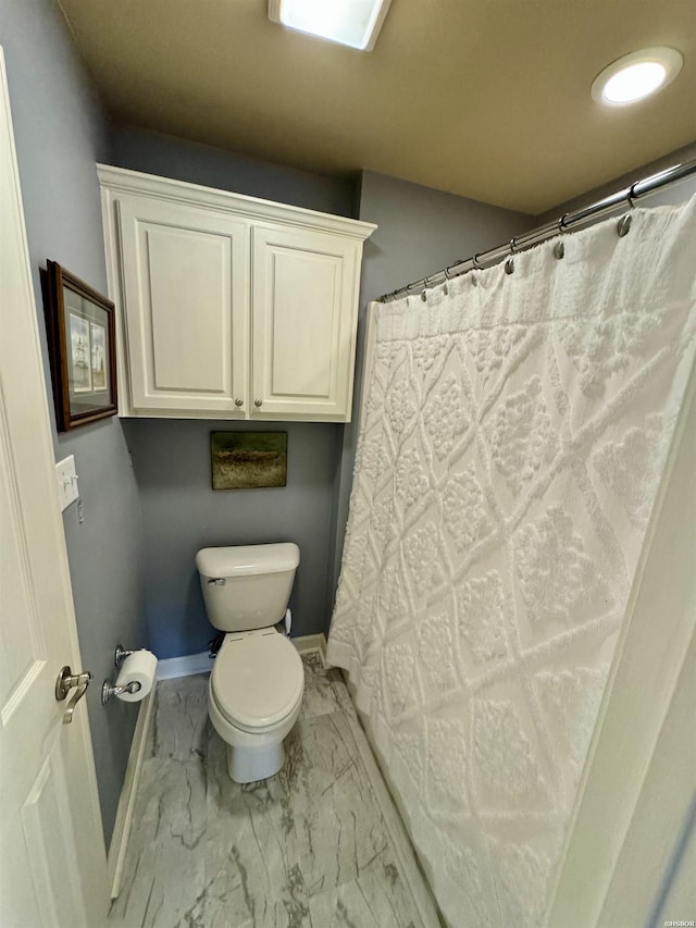 full bath featuring toilet, marble finish floor, and baseboards