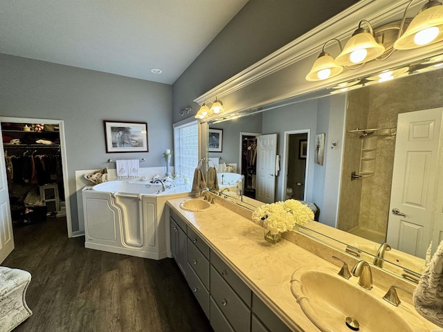 full bath featuring a garden tub, double vanity, a sink, wood finished floors, and tiled shower