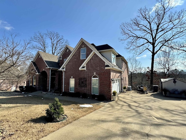 view of front of house with central air condition unit, an attached garage, concrete driveway, and brick siding