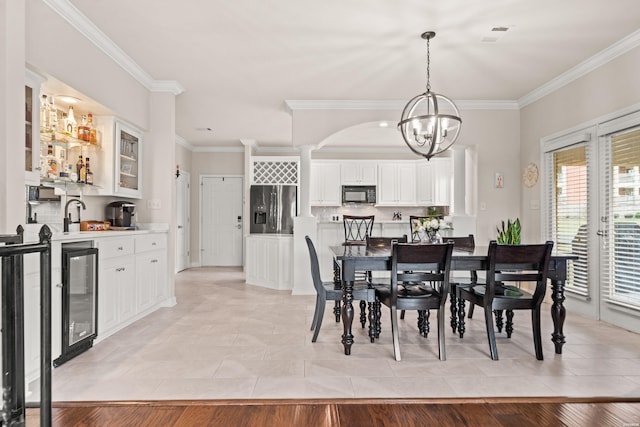 dining area featuring light tile patterned floors, beverage cooler, ornamental molding, wet bar, and a notable chandelier