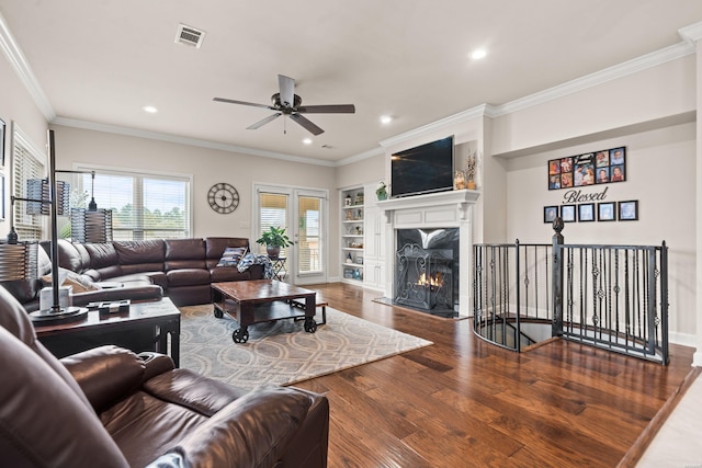 living room featuring crown molding, recessed lighting, visible vents, a premium fireplace, and wood finished floors