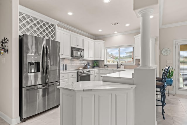 kitchen featuring stainless steel appliances, visible vents, white cabinetry, backsplash, and ornate columns