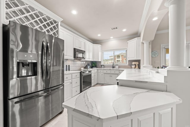 kitchen featuring stainless steel appliances, a peninsula, white cabinets, light stone countertops, and ornate columns