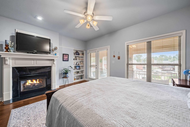 bedroom with ceiling fan, a premium fireplace, and wood finished floors