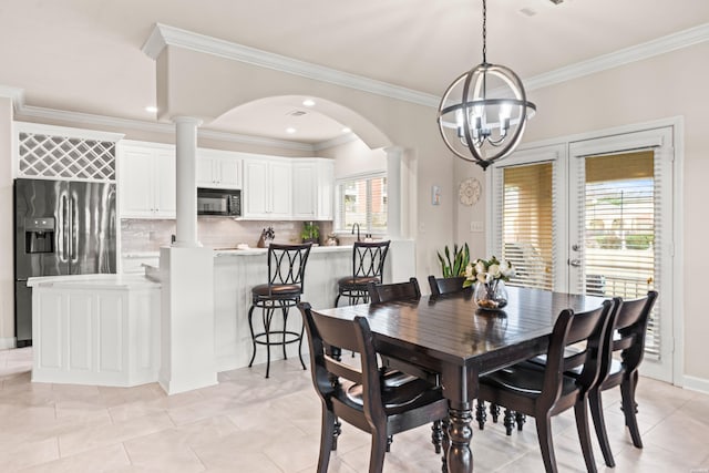 dining area with an inviting chandelier, decorative columns, ornamental molding, and arched walkways