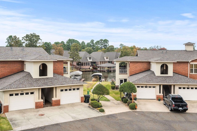 view of front of home featuring a garage, a residential view, a water view, and roof with shingles