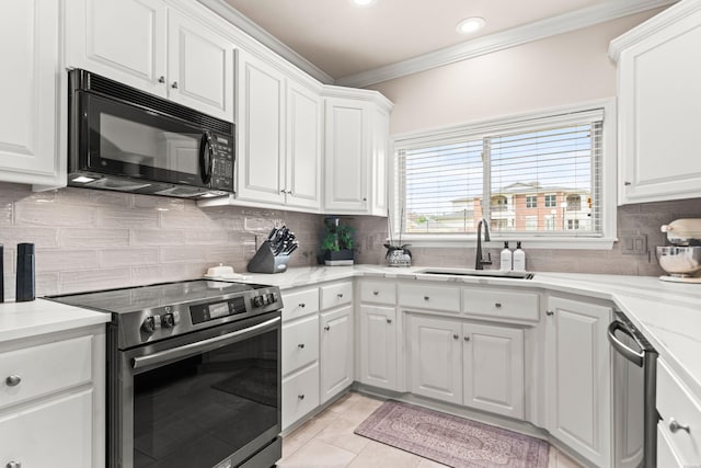 kitchen with light tile patterned floors, stainless steel appliances, ornamental molding, white cabinets, and a sink