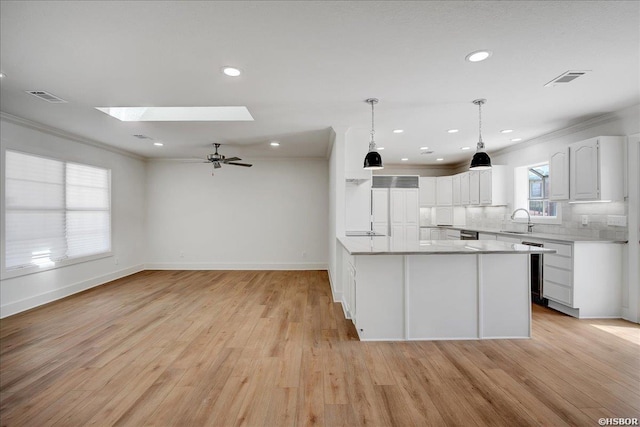 kitchen featuring decorative light fixtures, light countertops, visible vents, white cabinets, and a sink