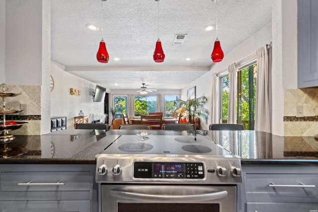 kitchen featuring gray cabinetry, open floor plan, stainless steel electric range, dark stone counters, and tasteful backsplash