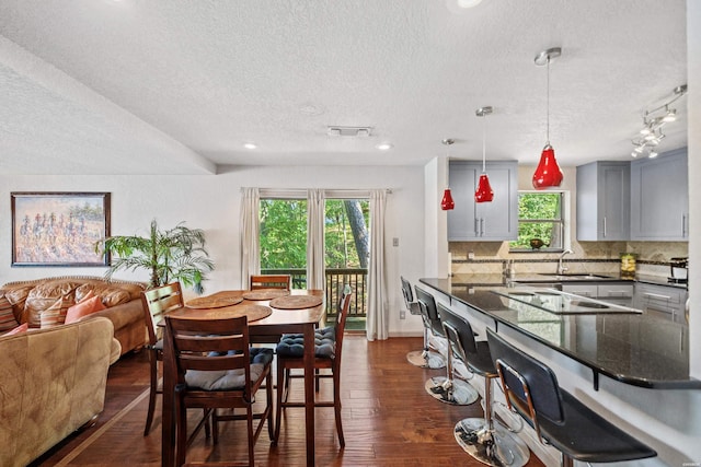 dining space with a textured ceiling, dark wood finished floors, visible vents, and rail lighting