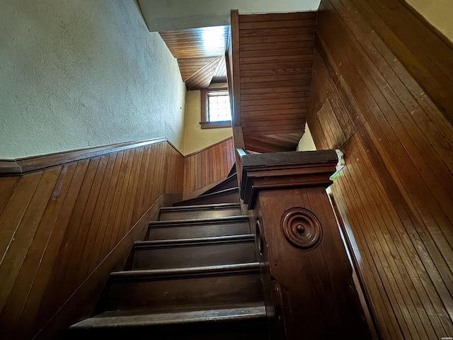 stairs featuring a textured wall and wooden walls